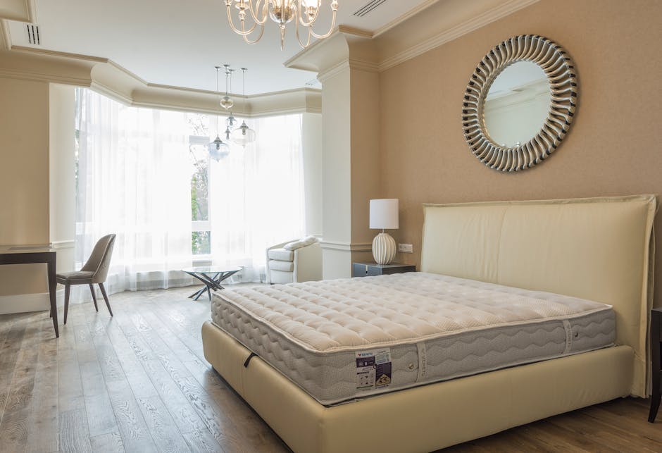 The image depicts a casual, outdoor setting featuring two mattresses placed directly on a concrete surface, suggesting an informal or temporary arrangement. The first mattress, positioned on the left,