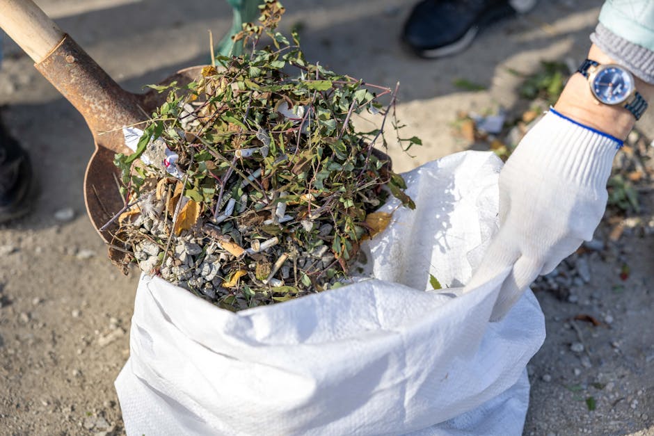 A large pile of tightly tied black plastic rubbish bags, predominantly filled with waste, stacked against a modern tiled wall exterior. Several clear plastic water bottles and other small pieces of tr